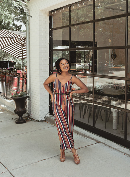 beautiful woman standing in front of a store smiling wearing a pantsuit