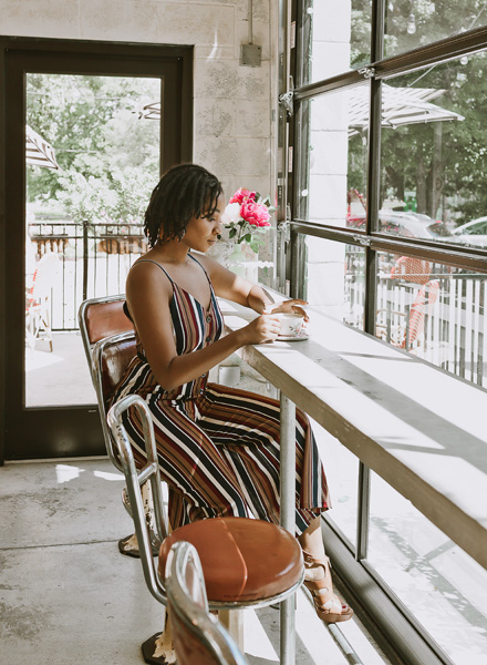 woman sitting at coffee bar looking at cup of coffee