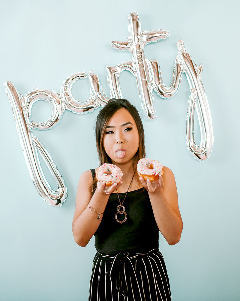 chinese girl wearing striped pants holding donut