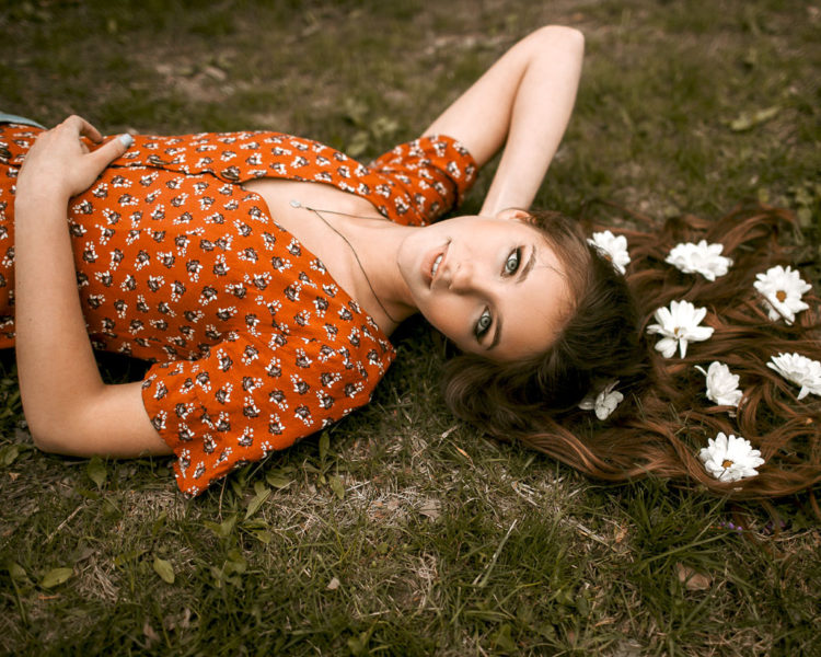 girl laying on grass with flowers in her hair