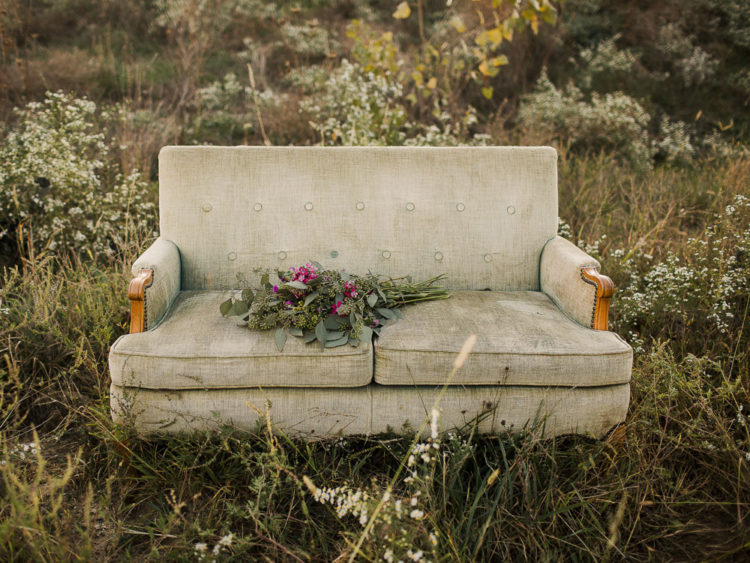 green couch in open field with flowers on cushion