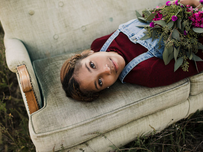 teenage girl laying on green couch holding flowers