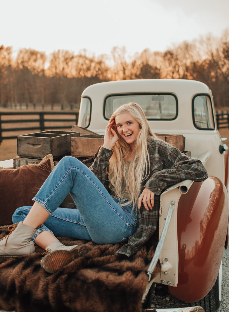 blonde girl sitting on tail bed of truck