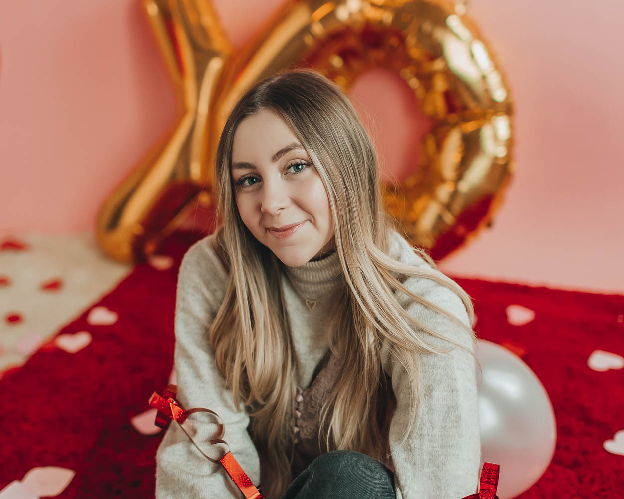girl sitting on red rug with valentines day decorations